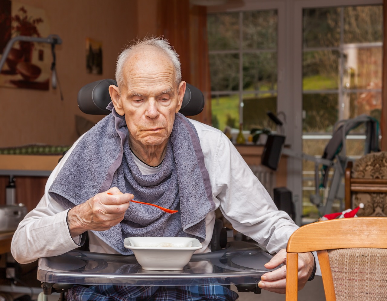 An older person being supported with a meal in an aged care dining room